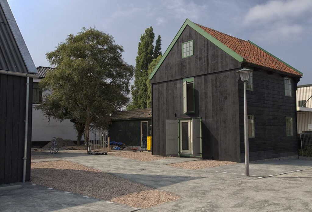 Zwart gepotdekselde houten schuur met groene daklijst