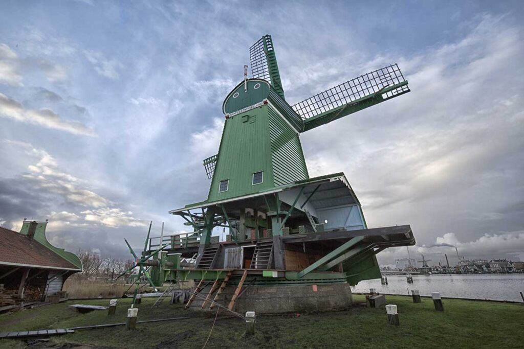 Groen geschilderde houten paltrokmolen aan het water