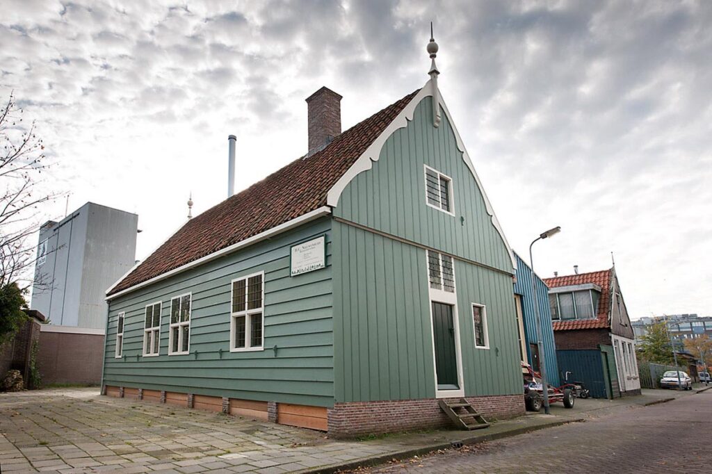 Groen houten Zaans woonhuis met witte topgevel en rode dakpannen aan de straat