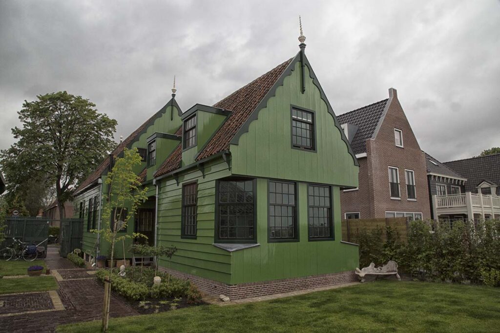 Groen houten Zaans woonhuis met gepunte topgevel en grote schuiframen